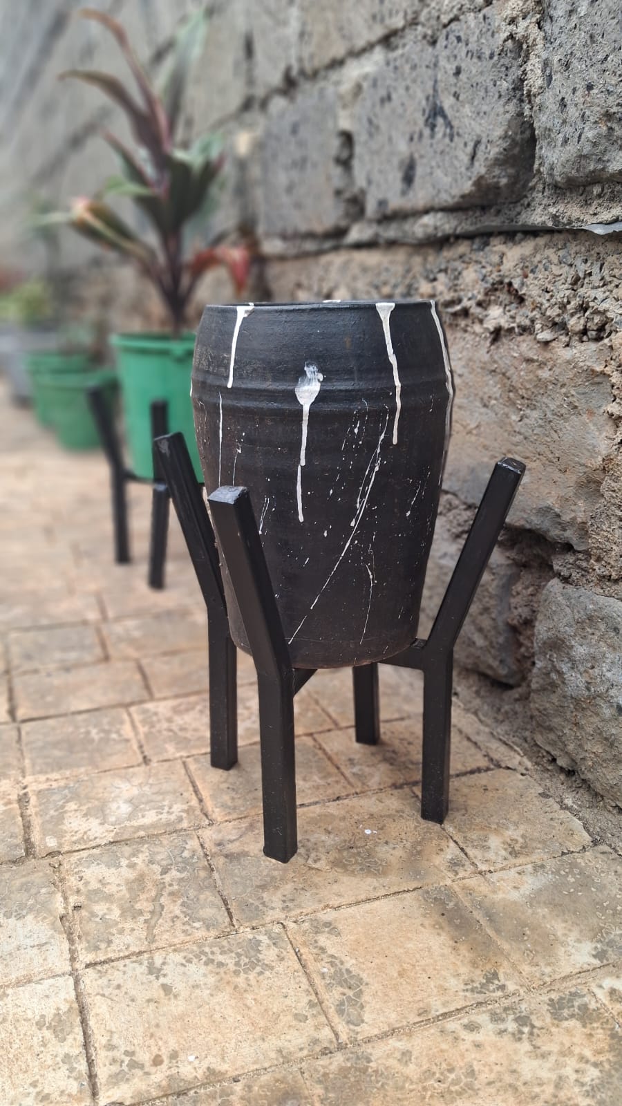 Premium black clay pot with white drip art on black metal stand – close-up view